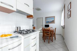 a white kitchen with a stove and a table at I Pungenti in Castiglioncello