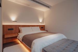 a bedroom with a large white bed and a bench at 峨眉山和院一溪清音酒店 in Emeishan City