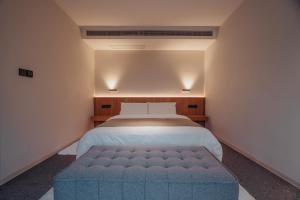 a bedroom with a large bed with a blue ottoman at 峨眉山和院一溪清音酒店 in Emeishan City