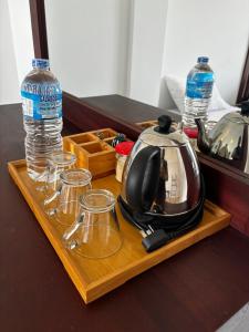 a tea kettle and glasses on a wooden tray with water at Kandy Hub Guest House in Kandy