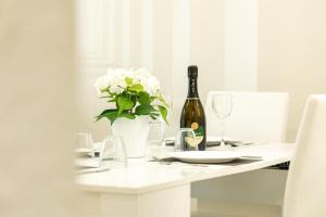 a white table with a bottle of wine and a vase of flowers at La Casa di Pan in Cremeno