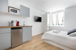 une chambre blanche avec un lit et une cuisine dans l'établissement STUDIOS cosy au centre-ville quartier Jaurès et Saint-Martin, à Brest 40 autres photos