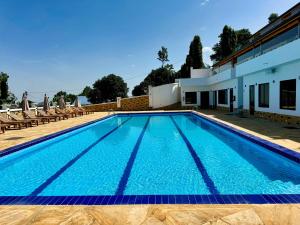 a large swimming pool with chairs and a building at Moshono Hillside in Arusha