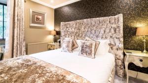 a bedroom with a white bed with a headboard at Derby Manor in Bournemouth +37 photos
