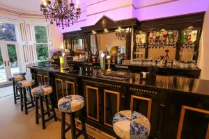 a bar with stools in a room with a mirror at Derby Manor in Bournemouth +109 photos