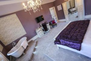 a bedroom with a bed and a tub and a sink at Derby Manor in Bournemouth