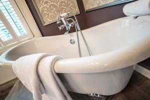 a white bath tub in a bathroom with towels at Derby Manor in Bournemouth