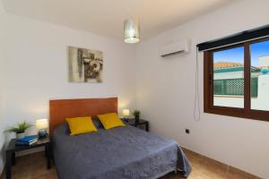 sypialnia z łóżkiem z żółtymi poduszkami i oknem w obiekcie Villa Maca by Villa Plus w Corralejo +16 zdjęć
