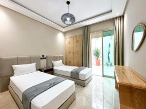 una camera d'albergo con due letti e una scrivania di Cosy Elegant Piscine a proximite a Tangeri