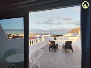 ein Balkon mit Stühlen und einem Tisch und einer Aussicht in der Unterkunft VolKKanrentals Casa La Hoya in Famara