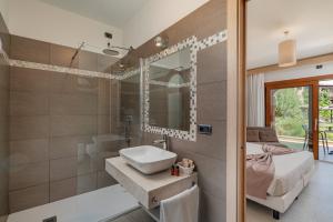 a bathroom with a sink and a bed and a mirror at Hotel Mariposas in Villasimius