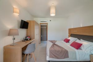 a bedroom with a bed and a desk with a computer at Hotel Mariposas in Villasimius