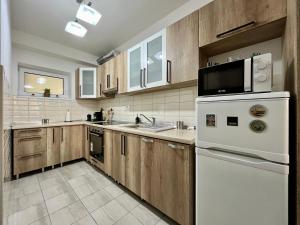eine Küche mit weißen Geräten und Holzschränken in der Unterkunft City Centre Simonffy Apartment in Debrecen + 16 Fotos