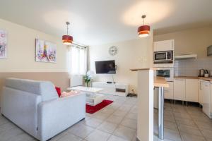ein Wohnzimmer mit Couch und Küche in der Unterkunft Fééria - Appartement au calme proche de Disneyland Paris in Chessy