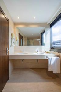 a bathroom with two sinks and a large mirror at Hotel Coia de Vigo in Vigo