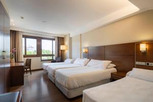 a hotel room with three beds and a desk at Hotel Coia de Vigo in Vigo