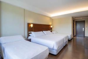 two beds in a hotel room with white sheets at Hotel Coia de Vigo in Vigo