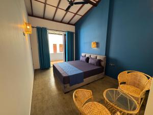 a bedroom with a bed and chairs and a window at Funky Hotel in Hikkaduwa