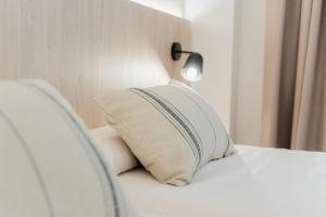 a white bed with a pillow on top of it at Minura Cala Galdana & Apartamentos d'Aljandar in Cala Galdana