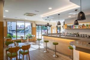 a restaurant with a bar with green stools at Hotel Coia de Vigo in Vigo