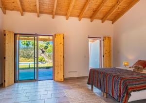 a room with a bed and sliding glass doors at Choeiro Verde - Casa de Campo na Costa Vicentina in Brejao +29 photos