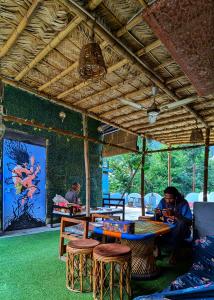 einem Mann, der an einem Tisch in einem Raum mit Tischen und Stühlen sitzt in der Unterkunft Hobbit House Hostel in Rishikesh