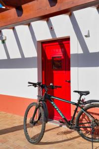 a bike parked in front of a red door at Choeiro Verde - Casa de Campo na Costa Vicentina in Brejao