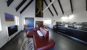 a living room with a red couch and a kitchen at The Beech Way Cottage in Cape St Francis