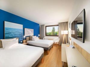a hotel room with two beds and a desk at Novotel Gdańsk Marina in Gdańsk