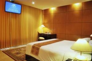 a hotel room with a bed and a tv on the wall at Royal Senyiur Hotel in Prigen +5 photos