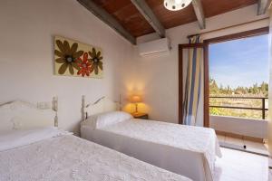 a bedroom with two beds and a window with a view at Villa Juana in Can Picafort +22 photos