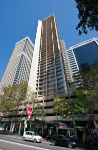 雪梨的住宿－柏偉詩城市中心酒店，一座高大的建筑,前面有汽车停放