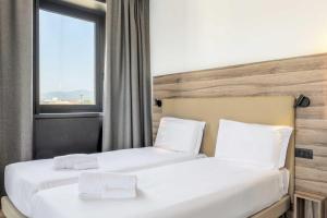 プラートにあるB&B HOTEL Prato City Centerのベッド2台 ホテルルーム 窓付