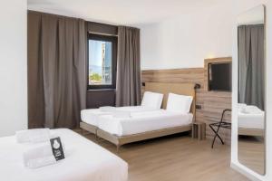 プラートにあるB&B HOTEL Prato City Centerのベッドが2つと鏡があるホテルの部屋