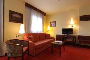 a hotel room with a couch and a desk and a television at RVHotels Tuca in Vielha