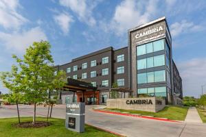 a building with a tree in front of it at Cambria Hotel Austin Airport in Austin