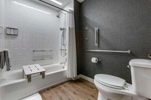 a bathroom with a toilet and a tub and a sink at Cambria Hotel Austin Airport in Austin