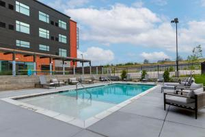 a swimming pool with chairs and a building at Cambria Hotel Austin Airport in Austin