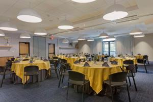 a conference room with tables and chairs with yellow table cloth at Cambria Hotel Austin Airport in Austin