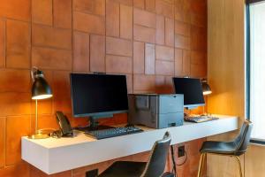 three computer monitors sitting on top of a desk at Cambria Hotel Austin Airport in Austin