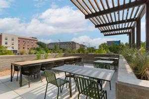 a patio with tables and chairs and a wooden pergola at Cambria Hotel Austin Airport in Austin
