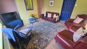 a living room with leather furniture and a tv at Dovetails, short drive from Alton Towers and Uttoxeter racecourse Games room with Wii and football table in Rocester