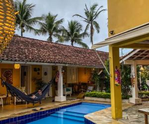 a man lying in a hammock in front of a house at Canto das Laranjeiras MOA in Guarujá