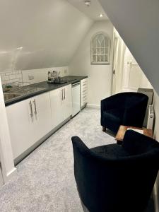 a kitchen with white cabinets and black counter tops at The Harvard Inn in Stock