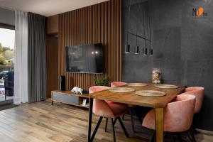 ein Esszimmer mit einem Holztisch und rosa Stühlen in der Unterkunft Apartamenty Premium STONE HILL - Baseny&Jacuzzi in Szklarska Poręba