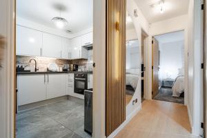 a kitchen with white cabinets and a room with a bed at The Pad in Paisley