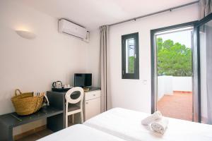 a bedroom with a bed and a desk and a window at Club Cala Azul in Cala Llenya