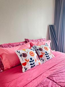a pink bed with two pillows on it at AVALYN Room Plus III - East Ville in Ban Hua Khao Sammuk