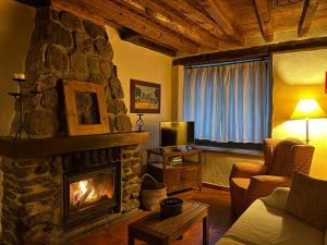 salon z kamiennym kominkiem i telewizorem w obiekcie Casa rural Álamo - Valle de El Paular w mieście Rascafría