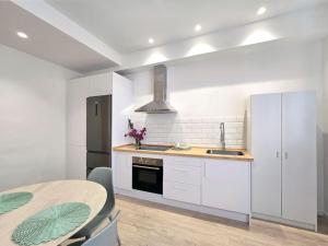 a kitchen with white cabinets and a table and a sink at San Basilio in Murcia